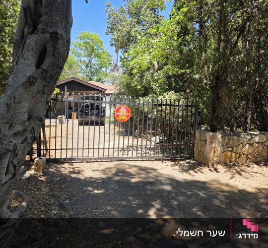 שער חשמלי שחור ממתכת בכניסה לחצר בית פרטי